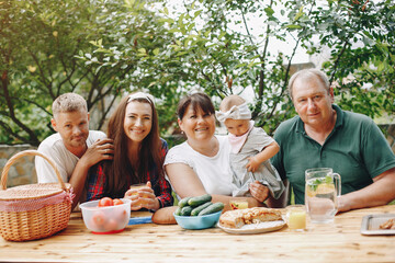 Family sitting in the yard. Mother and little daughter near the house. Big family on a picnic