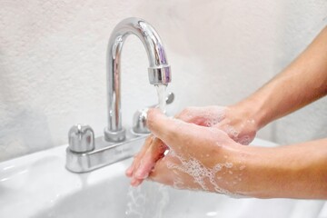 Sticker - Selective focus shot of the male washing hands with soap over a sink in the bathroom