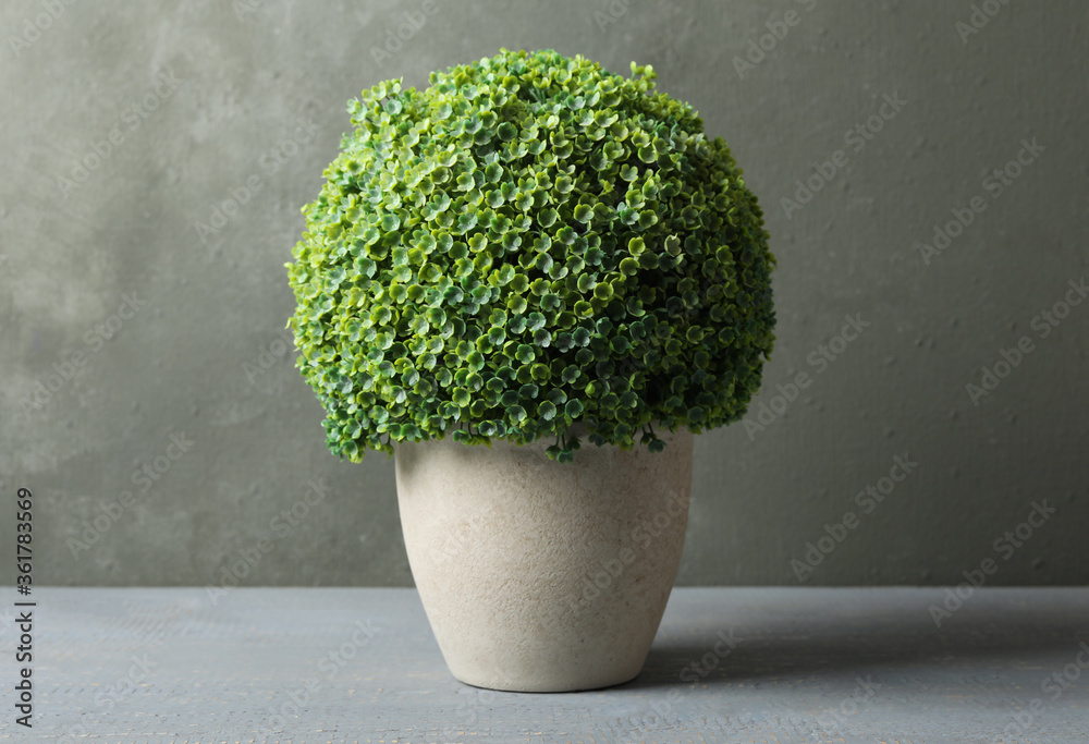 Artificial plant in ceramic flower pot on grey wooden table - obrazy, fototapety, plakaty 