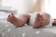 © New Africa - Cute little baby in diaper lying on bed in room, closeup