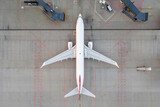 Fototapeta  - Top down view on comercial airplane docking in terminal in the parking lot of the airport apron, waiting for services maintenance, refilling fuel services after airspace lock down