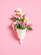 Menstrual cup eco-friendly reusable and silicone and flowers isolated on a pink background