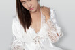 Shoulder pain or dislocated shoulder in a woman, Ache pinched nerve in the neck or shoulder, Lady wearing white nightgown & long sleeve satin robe with floral lace have scruff pain on gray background.