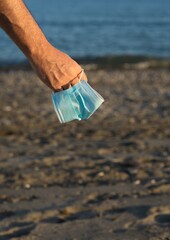 Sticker - Vertical selective focus shot of male hands holding a face mask on the beach