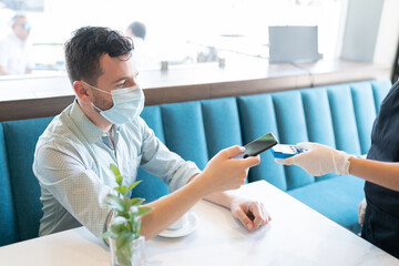 Wall Mural - Man Paying Through Smartphone In Cafe