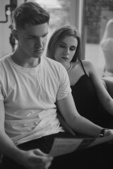 Wall Mural - Couple on the couch black and white photo, stylish photo of love. Fashion photo of a couple, blonde girl with a guy. Perfume, love is in the air.