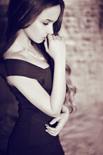 Girl In A Dress And Necklace Is Sad In Sepia. Black White Photo Of A Girl With Long Hair.