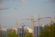 Inside place for many tall buildings under construction and cranes under a blue sky working on place with tall homes