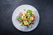 Traditional barbecue scallops with tomatoes, lettuce and Italian parmesan cheese offered as top view on a modern design plate with copy space