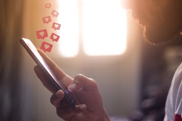 man holding smart phone in house with heart icons hovering over the screen social media concept