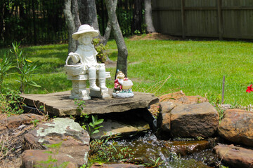 Pond statues of little girl and grumpy dwarf.