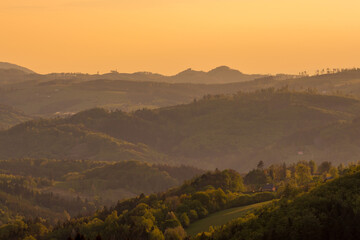 Canvas Print - Sunrise over the mountain area covered with fog orange rays penetrate the landscape.