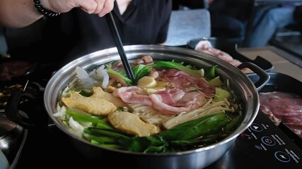 Wall Mural - Woman eating meat and vegetables by chopsticks , shabu is Korean or Japanese style beef in hot pot dish of thinly sliced meat and vegetables boiled in water. delicious food most popular in Thailand.