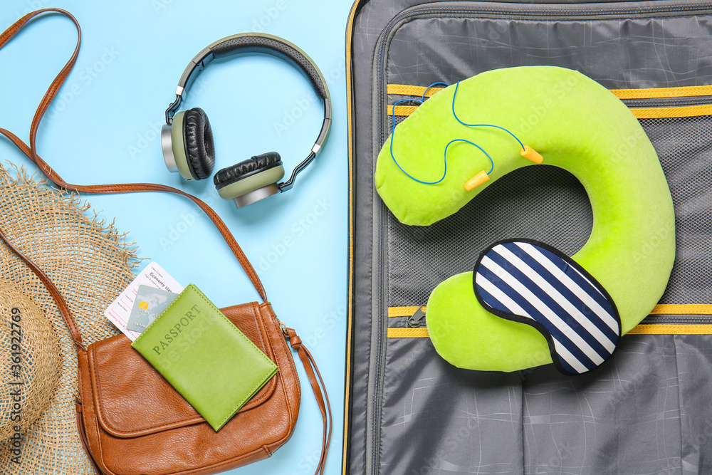 Suitcase with travel accessories on color background