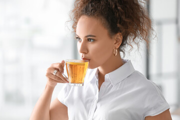 Beautiful young African-American woman drinking hot tea at home