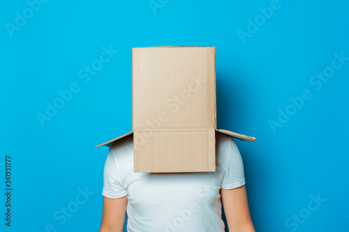 Fotomural Young man in a white T-shirt with a cardboard box on his head on a blue backgrou