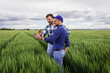 © Zoran Zeremski - Two farmers standing in green wheat field examining crop during the day.