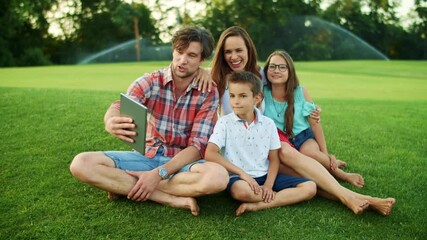 Wall Mural - Family having conversation by video chat on pad in park. Family using tablet