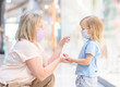 © Ermolaev Alexandr - Woman applies sanitizer for cleaning baby hands in a public place - in a shopping center or airport