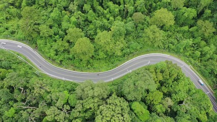 Canvas Print - Scenic road through forest with traffic driving. Aerial footage of cars and motorcycles on journey through countryside