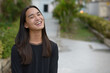 © Ranta Images - Happy young Asian man with long hair smiling at the park