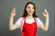 © Catalin Pop - Portrait of young female supermarket employee making double fingers crossed