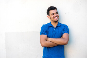 handsome young mixed race man smiling with arms crossed against white background