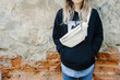 White Leather Fanny Pack, Leather Belt Bag Women. Model on a background of an old wall with a designer banana bag. Copy space for text. 