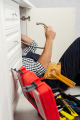 Wall Mural - Selective focus of workman holding metal pipe near open toolbox while fixing kitchen sink