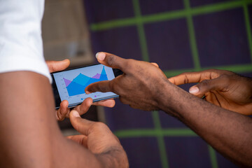 two young black people viewing a graph on a mobile phone , contemplating ideas, planning