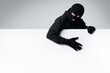 © Prostock-studio - Masked thief holding white blank advertising board