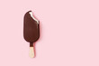 Helado de chocolate de palo batuta con una mordida sobre un fondo rosa pastel liso y aislado. Vista superior. Copy space