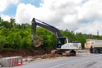 Wall Mural - Many heavy heavy industrial road construction machinery on new highway road construction site sunny day with blue sky background. Tipper dumper truckand excavator machine building freeway