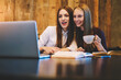 © BullRun - Smiling best friends watching funny videos on modern laptop device while enjoying tasty coffee during exam preparation sitting in coworking space.Copy space area for your advertising text message