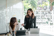 © amnaj - Two young beautiful asian business woman in the conversation, exchanging ideas at work.
