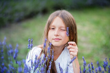 Wall Mural - Beautiful girl with long hair at sunset in the park. Girl in the lavender field. The child walks in nature. Summer sunsets
