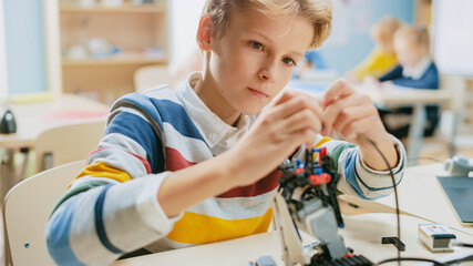 smart schoolboy builds / constructs small robot and uses laptop to program software for robotics eng