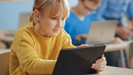 Poster - Elementary School Computer Science Class: Cute Girl Uses Digital Tablet Computer, Her Classmates work with Laptops too. Children Getting Modern Education in STEM, Playing and Learning