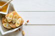 © Vitalii Zahorskyi - snack, peanut butter, banana and honey sandwich on a white wooden table, free space for writing text top view