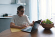 © stokkete - Woman sitting at the kitchen table and connecting with her laptop