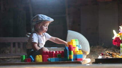 Poster - Cute beautiful child, blond kid, reading book and playing with construction blocks in a cozy attic room, filled with light