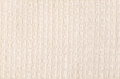Beige knitted fabric texture background, machine knitting texture. Light bedcover close-up