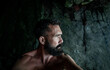 A bearded man looks out of a cave during the coronavirus outbreak