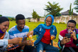 © Courage - young black people sitting in a park, drinking from their glass cups and using smartphone