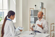 © Studio Romantic - Male patient pensioner speaks with the doctor at the desk in the office of the hospital.