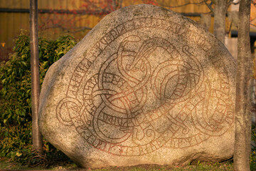 ancient rune stone with painted Midgaardsnake and runic inscriptions in Trelleborg, viking art