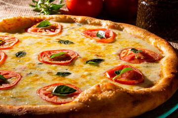 Pizza Margherita on wood background. Pizza Margarita with Tomatoes, Basil and Mozzarella Cheese close up. Traditional Brazilian Pizza.