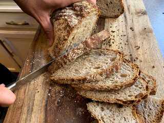 Homemade Bread being Sliced on a Wooden Cutting Board During Covid19