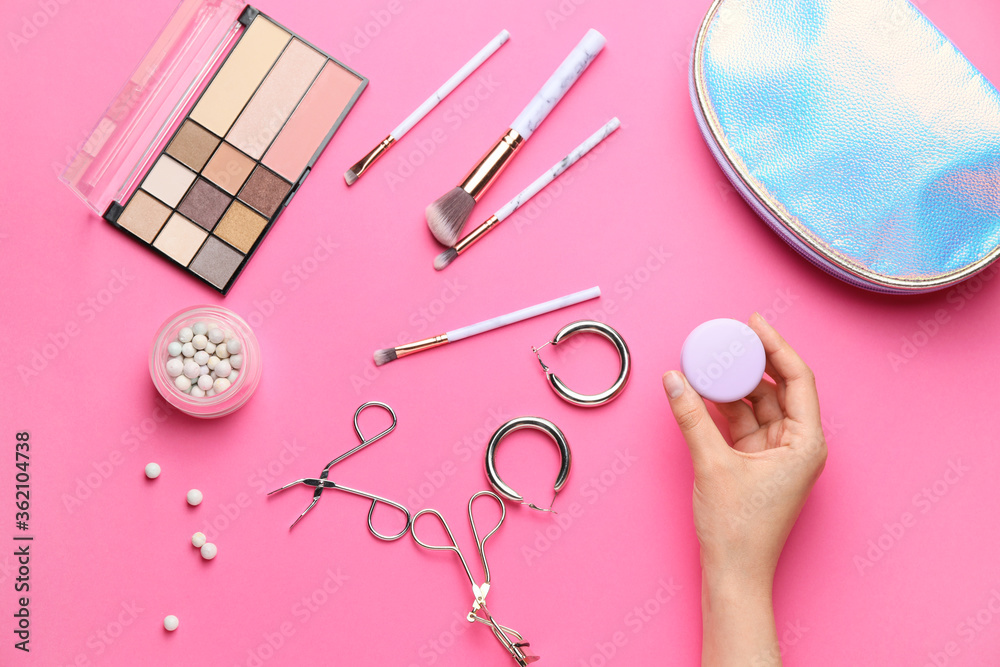 Female hand and bag with decorative cosmetics on color background