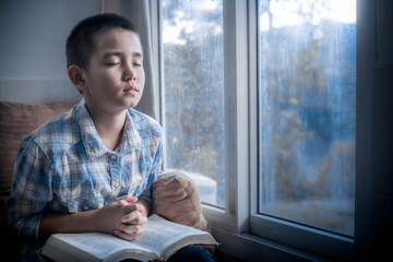 Sticker - Boy praying and Seek God with the holy Bible in morning at home. Children's beliefs of christian concept.